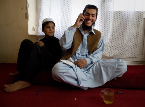 Mohammed Jawad talks on the phone to a friend as a relative looks on in his family home on September 25, 2009 in Kabul, Afghanistan. He was the youngest Guantanamo Bay prisoner only 17 when he was arrested six years ago, but his lawyer says he was 14 and family members say he was 12. JawadÕs conviction was for throwing a hand grenade at two U.S. soldiers. The judge said his confession was obtained under torture. © Paula Bronstein/Getty